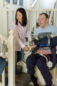 Man using stair lift with the help of his personal carer